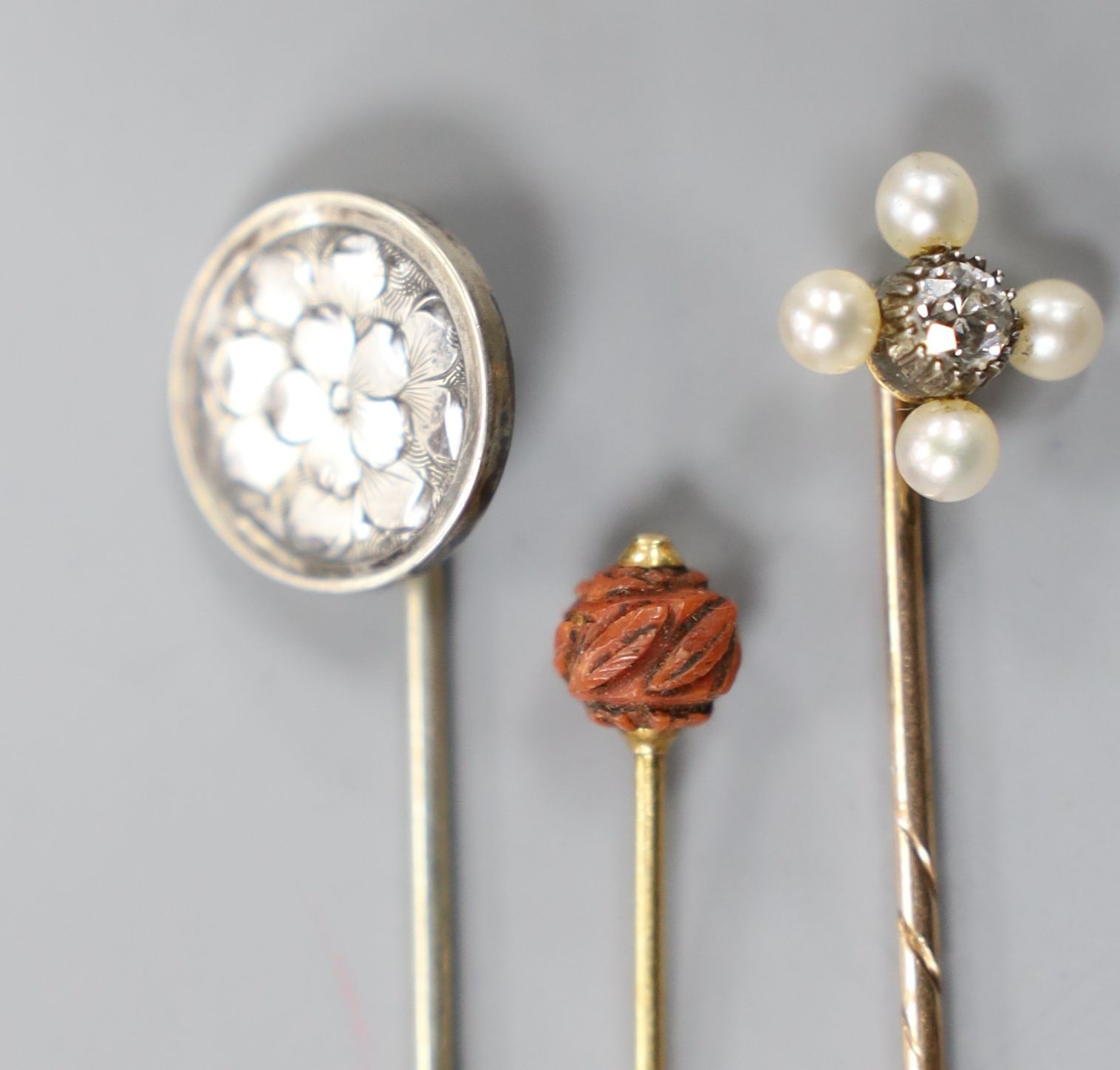 An Edwardian yellow metal, seed pearl and diamond set stick pin, 57mm and two other stick pins.